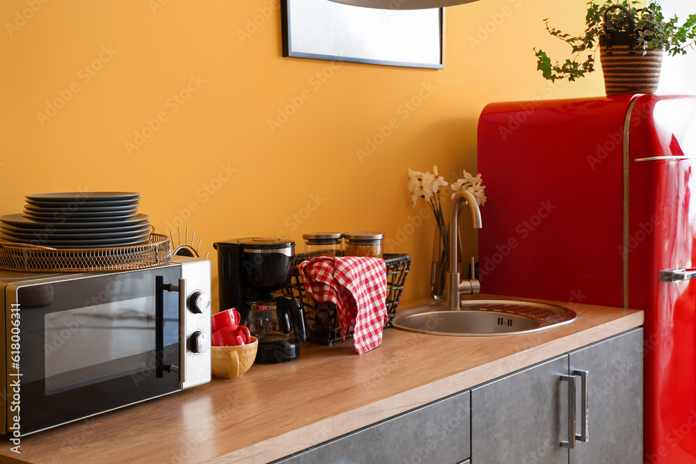 Interior of kitchen with red fridge, counters, microwave oven and utensils