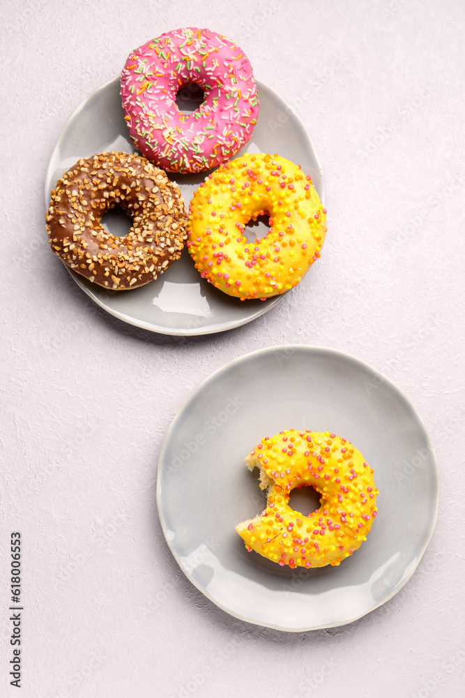 Plates with sweet donuts on light background