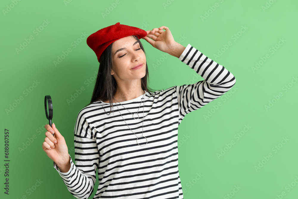 Beautiful happy young woman with magnifier on green background