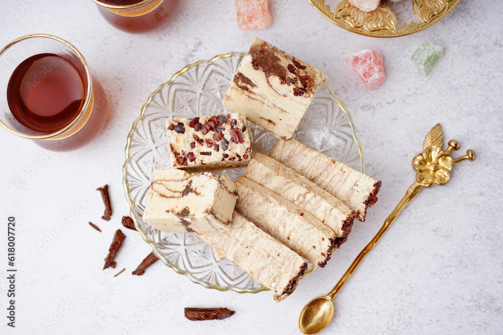 Pieces of tasty marble halva and glass with Turkish tea on light background