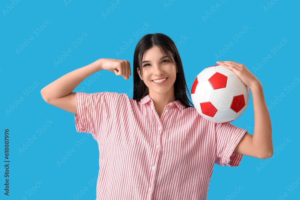 Sporty young woman with soccer ball on blue background