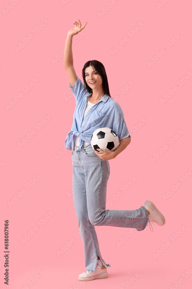 Young woman with soccer ball on pink background