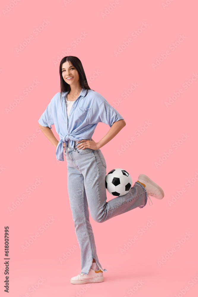 Young woman with soccer ball on pink background