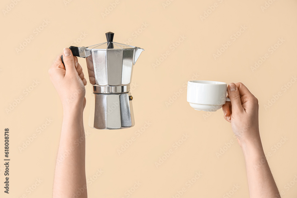 Female hands holding cup and geyser coffee maker on beige background