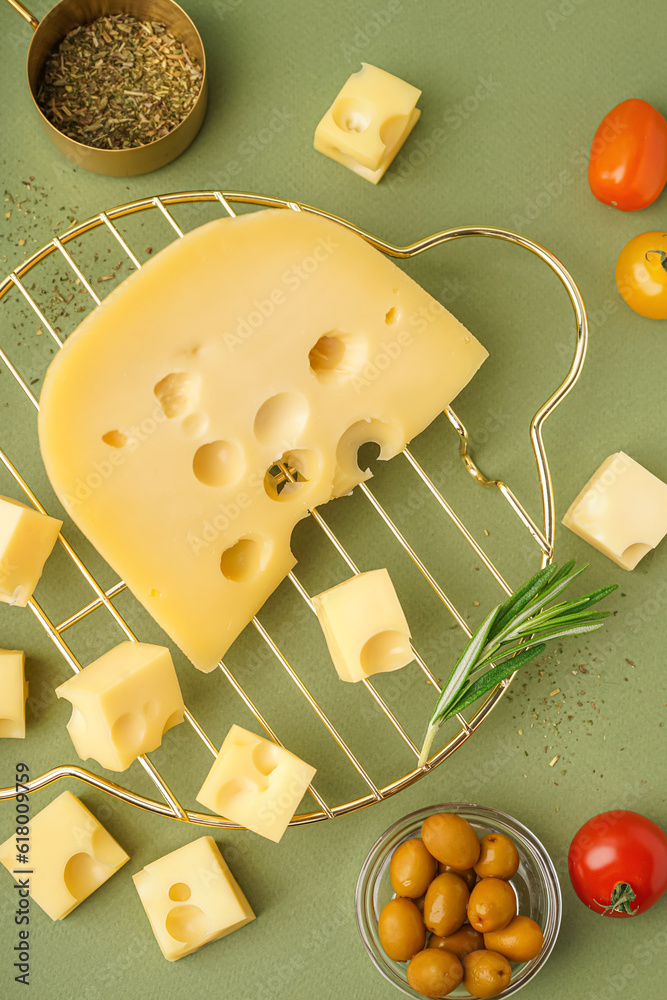 Stand with pieces of Swiss cheese and olives on green background