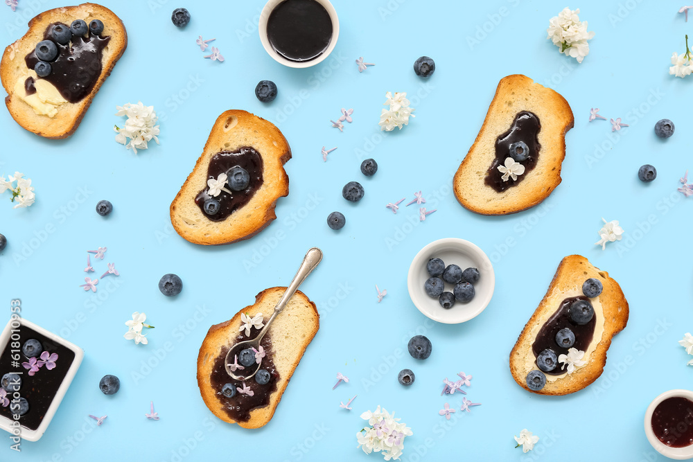 Composition with delicious jam toasts, blueberries and flowers on blue background