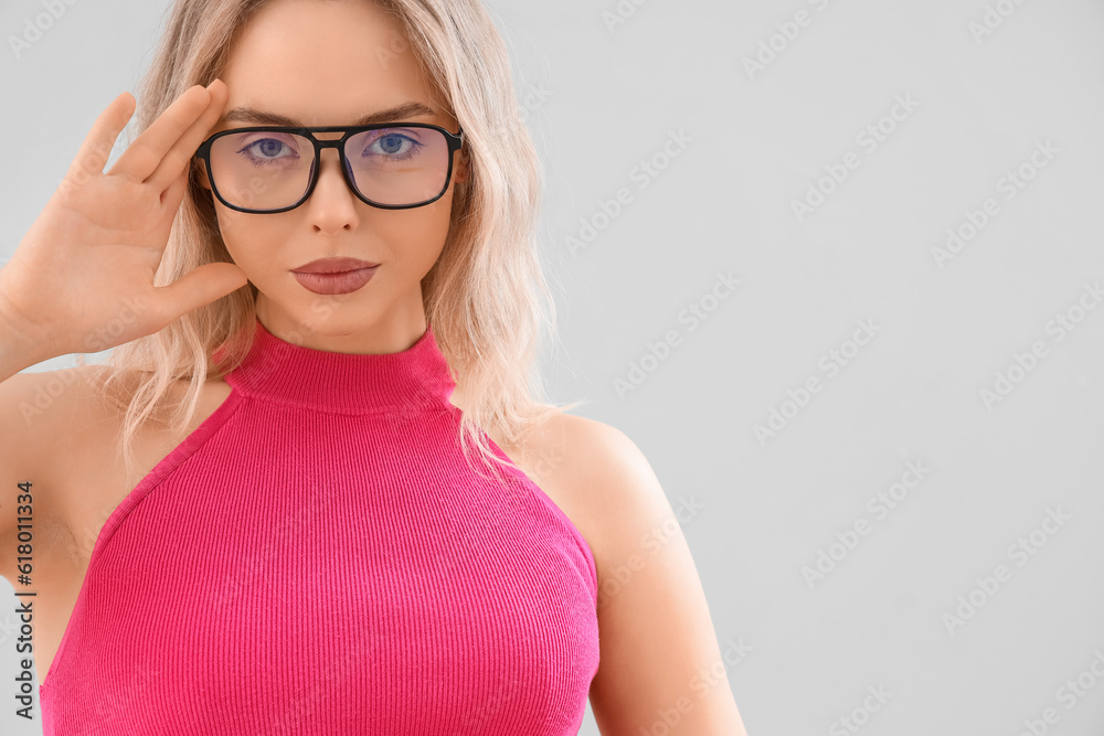 Young woman in stylish eyeglasses on light background, closeup