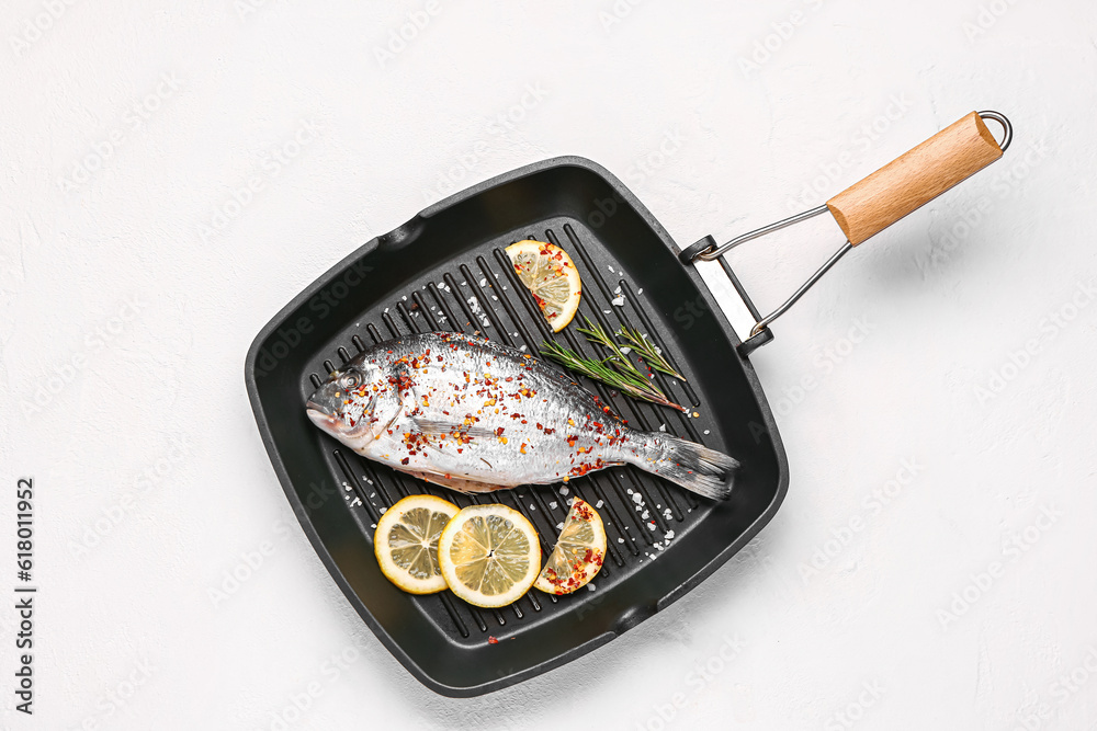 Grill pan of raw dorado fish with lemon on light background