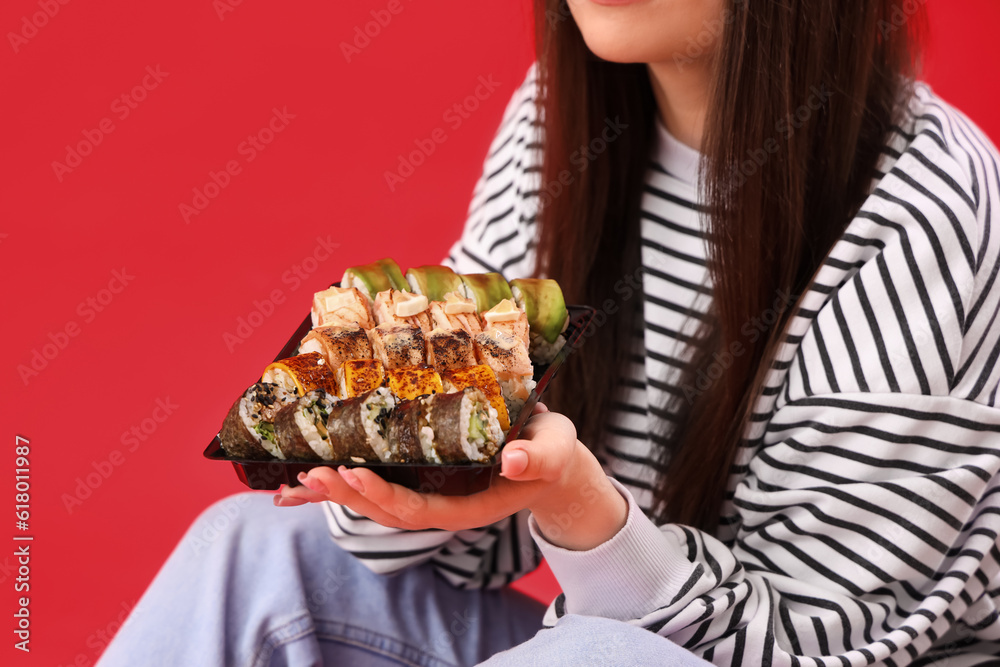 Young woman with sushi sitting on red background, closeup