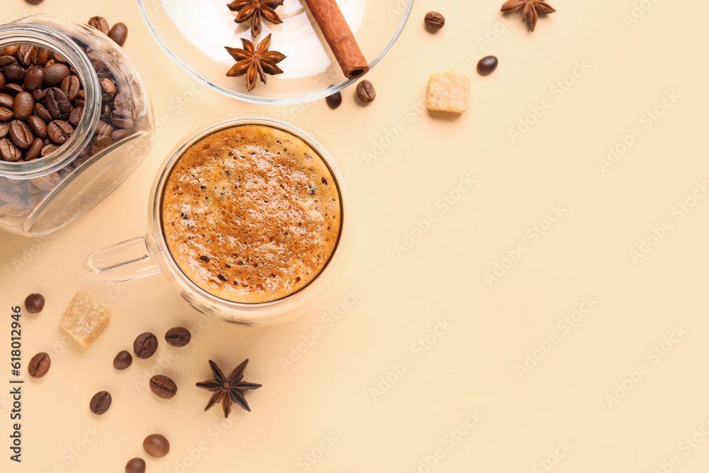 Glass cup of hot espresso and jar with coffee beans on beige background