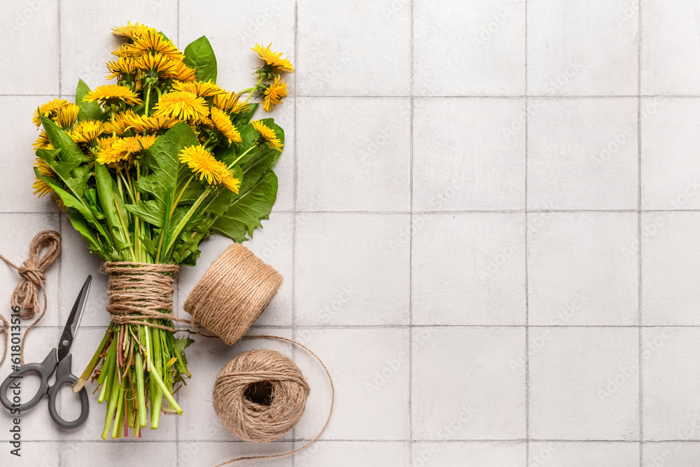 Bouquet of beautiful dandelion flowers, rope and scissors on light tile background