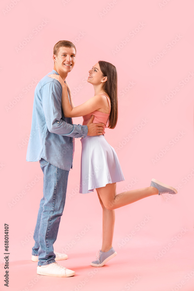 Happy young couple hugging on pink background