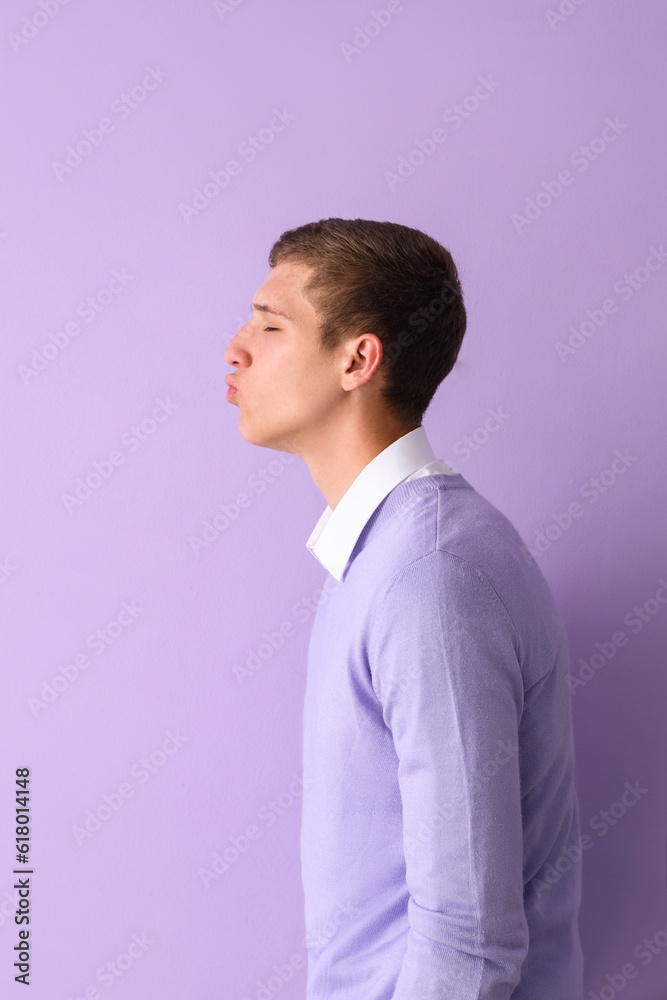 Young man blowing kiss on lilac background