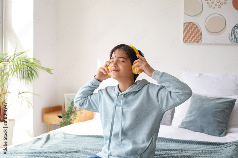 Little boy with headphones listening to music in bedroom