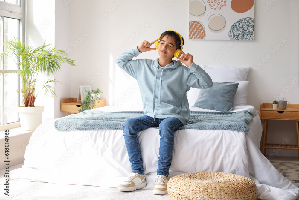 Little boy with headphones listening to music in bedroom