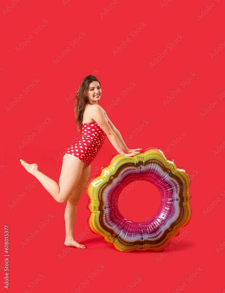 Young woman with swim ring on red background