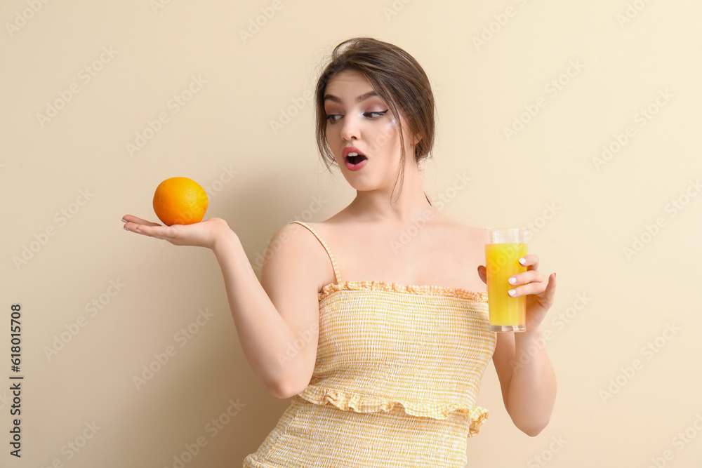 Shocked young woman with glass of juice and orange on beige background