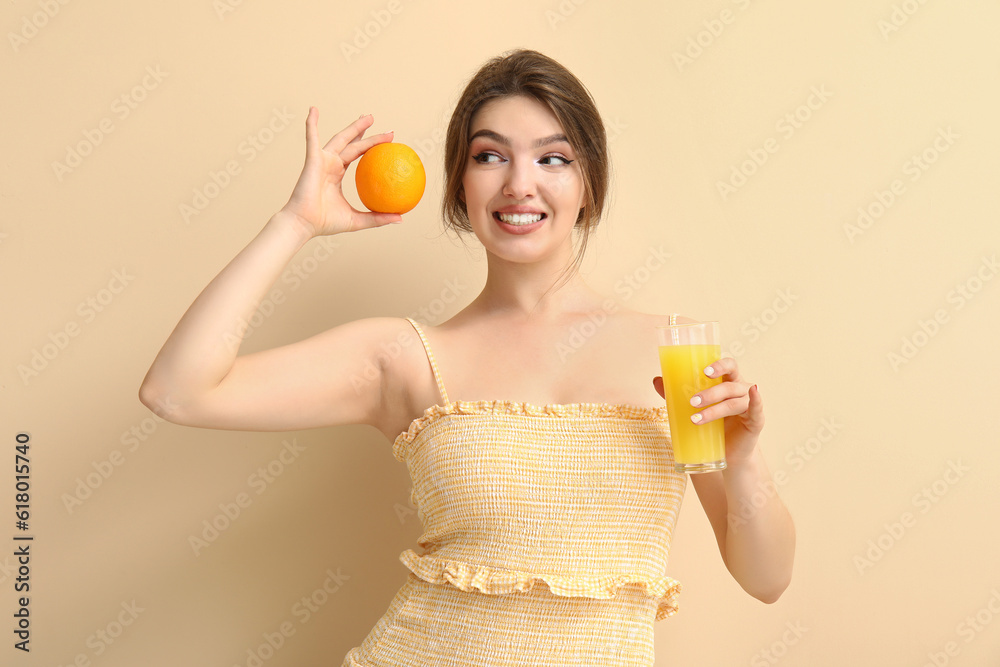 Young woman with glass of juice and orange on beige background