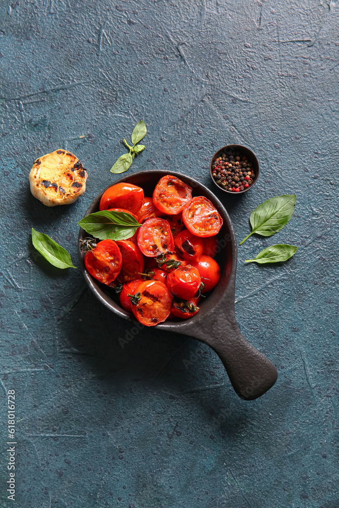 Bowl with tasty grilled tomatoes and basil on dark background