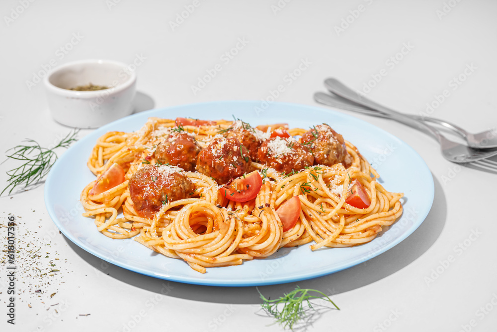 Plate of boiled pasta with tomato sauce and meat balls on white table