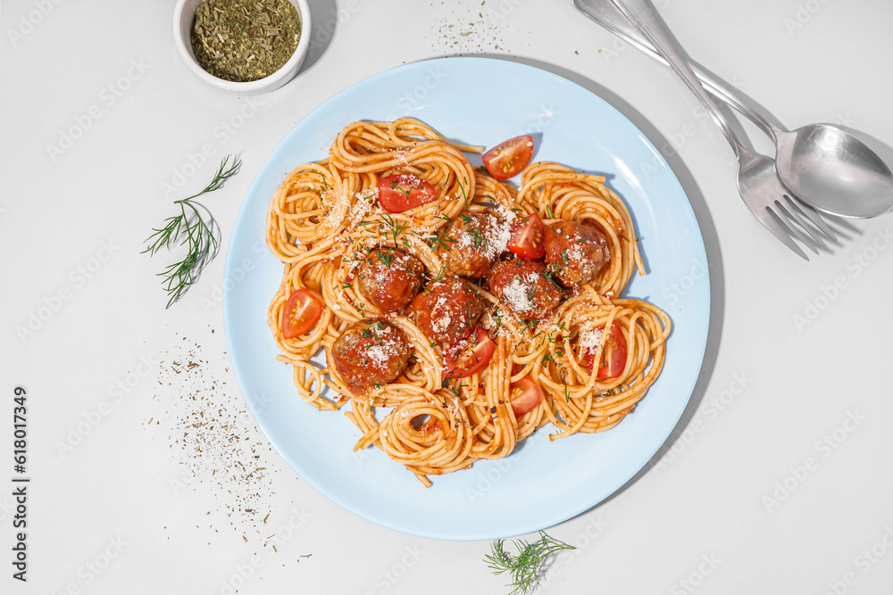 Plate of boiled pasta with tomato sauce and meat balls on white table