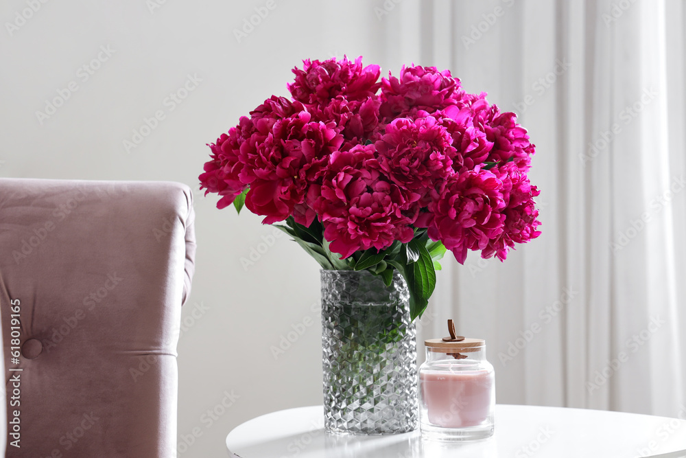 Vase of red peonies with candle on coffee table in living room