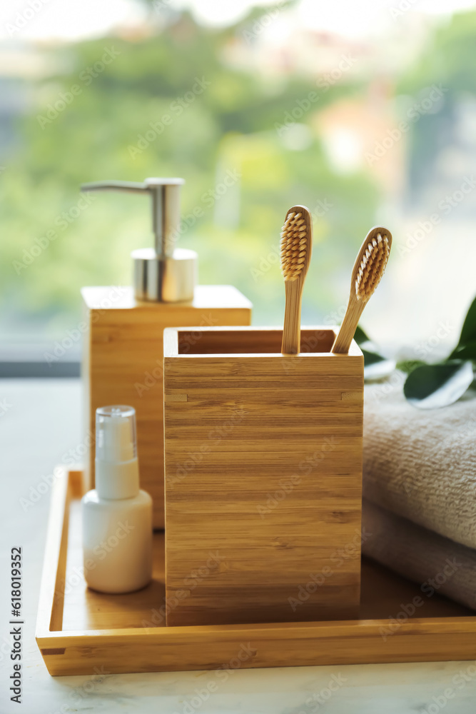 Bamboo tooth brushes and toiletries on windowsill in bathroom