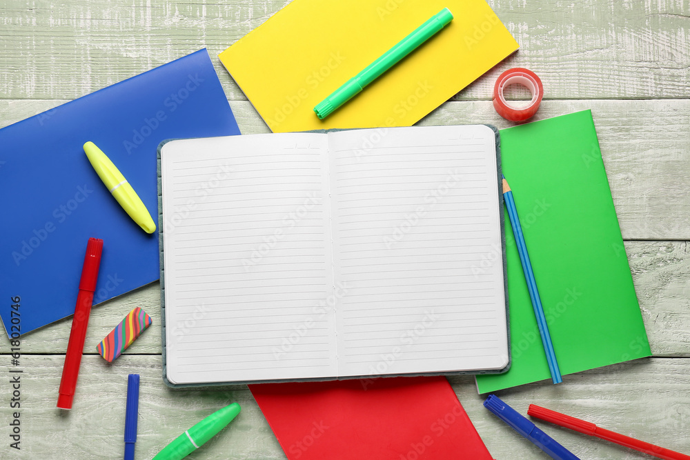 Notebooks with different stationery on wooden background