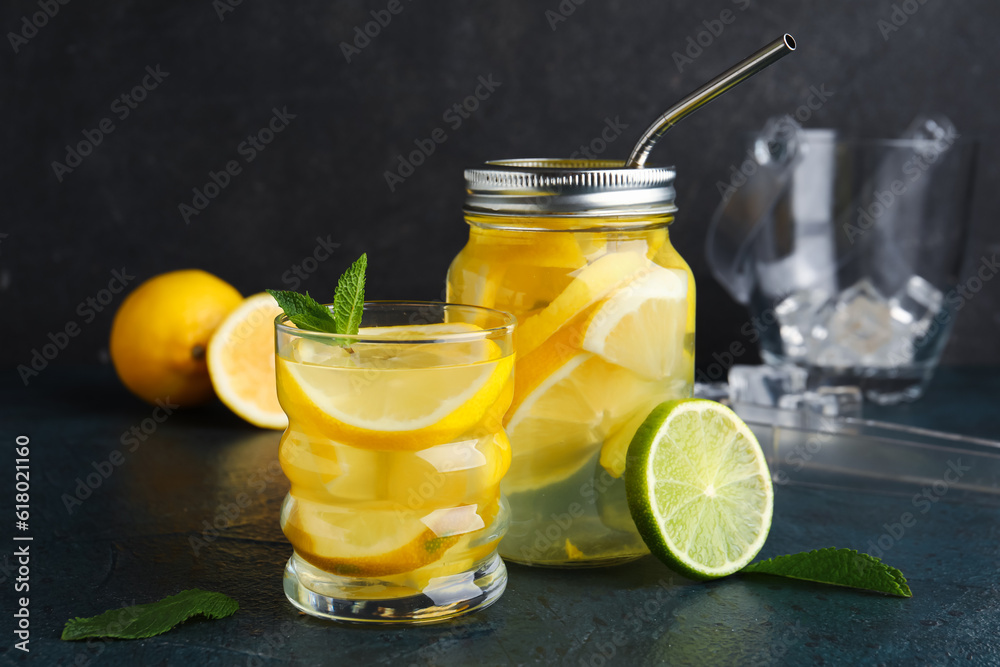 Glass and mason jar of infused water with lemon on black background