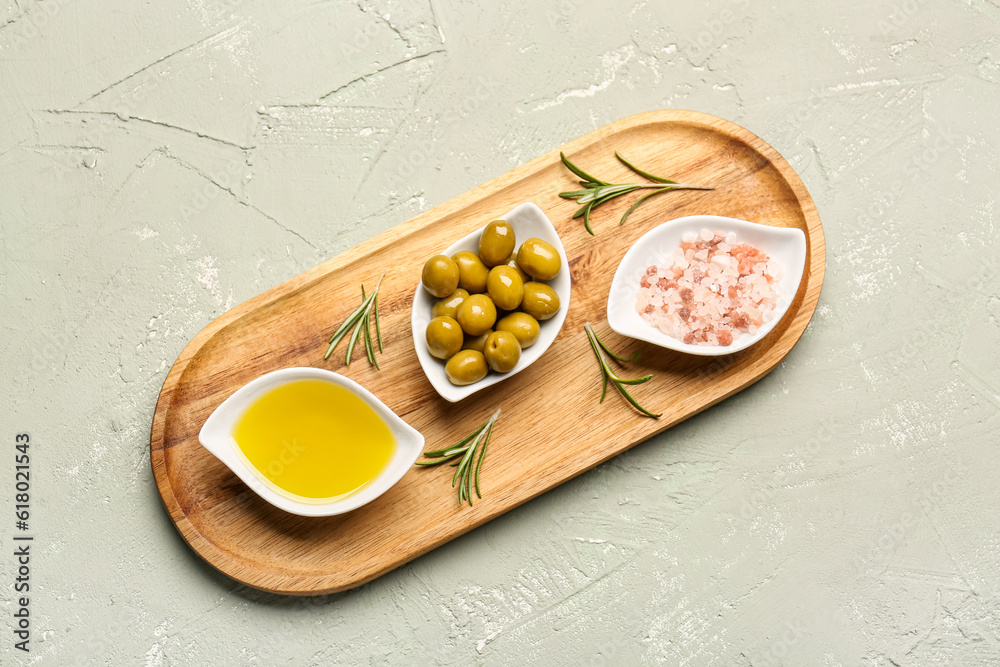 Bowls with ripe olives, salt and oil on light background