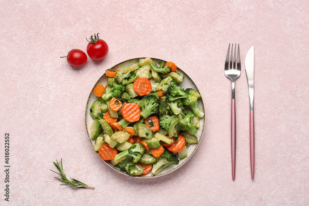 Plate with tasty fried vegetables on pink background