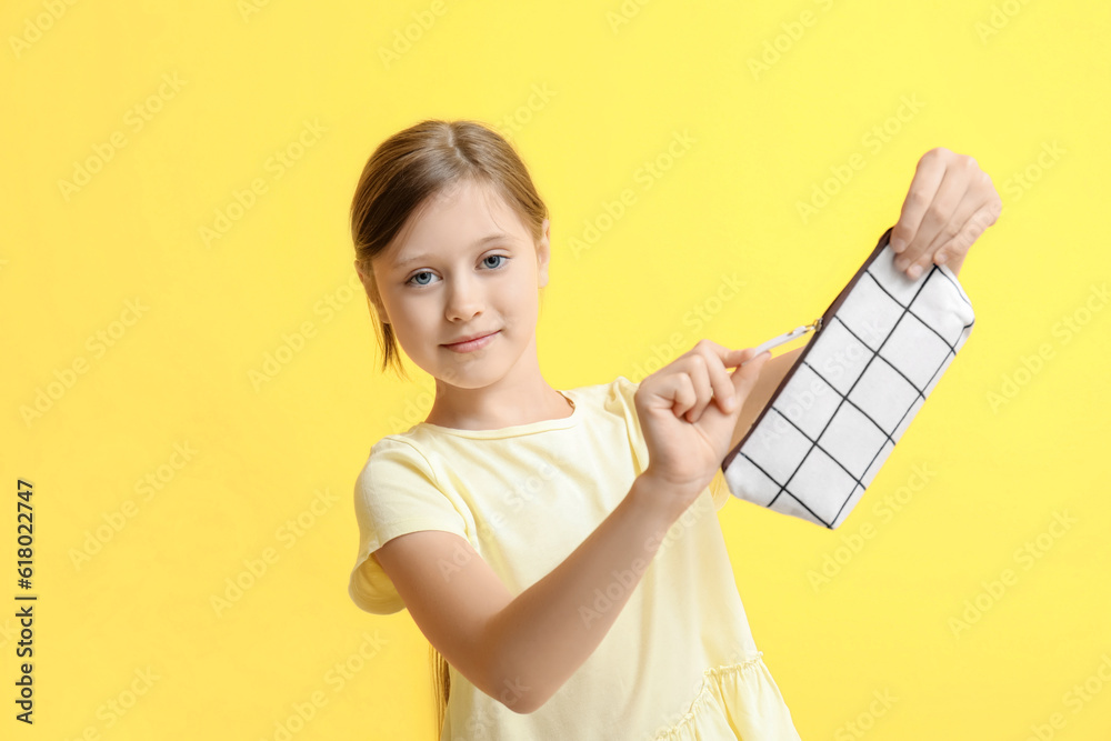 Little girl with pencil case on yellow background