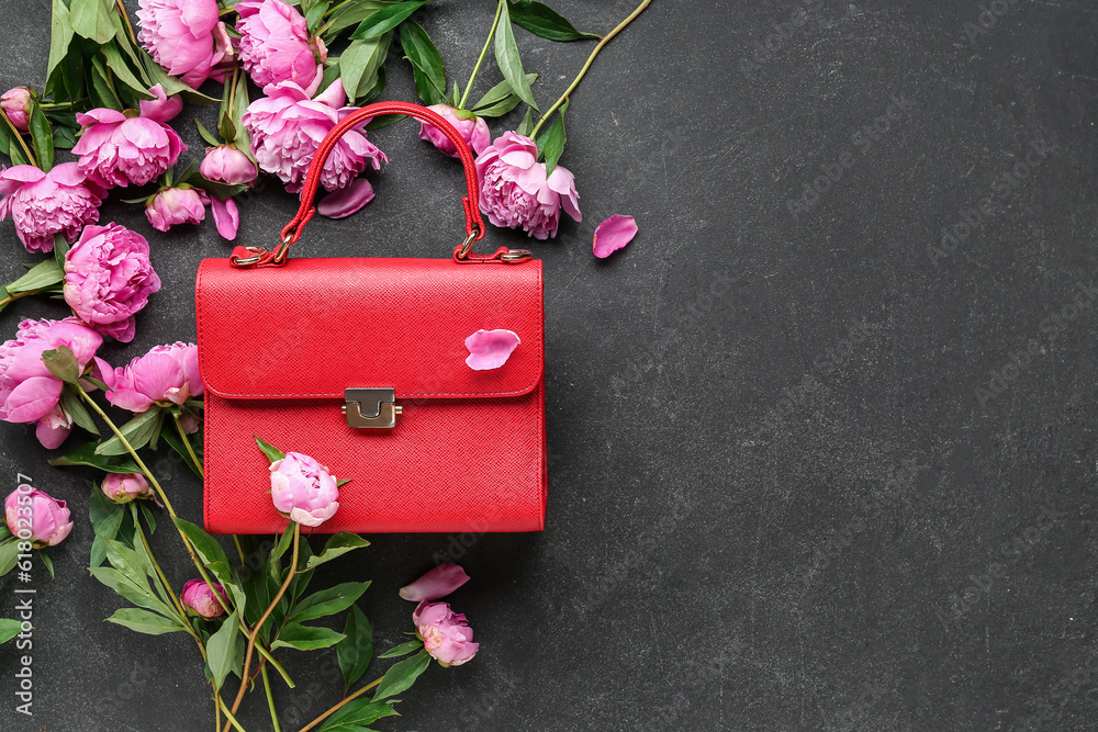 Composition with stylish female bag and beautiful peony flowers on dark background