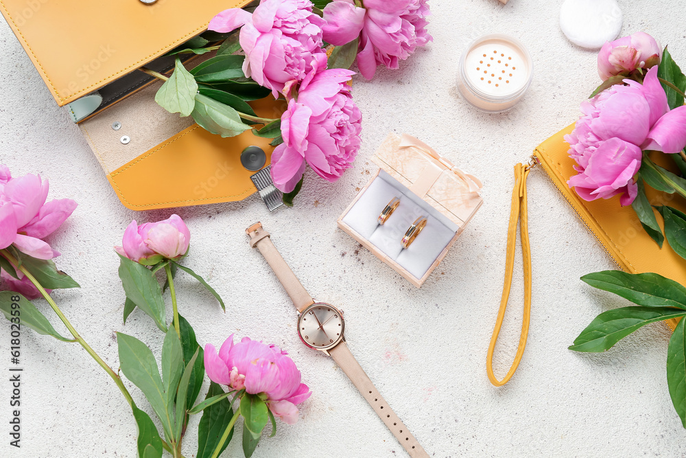 Composition with wedding rings, female accessories, cosmetics and beautiful peony flowers on light b