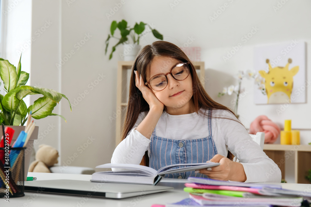 Little girl reading schoolbook at home