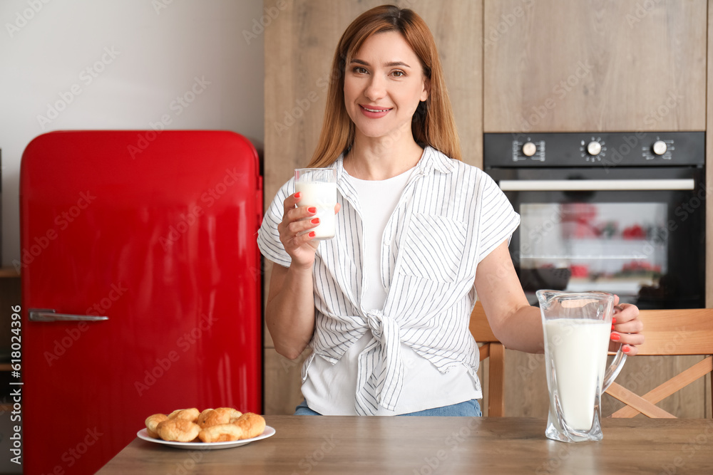 Young woman with glass and jug of milk in kitchen