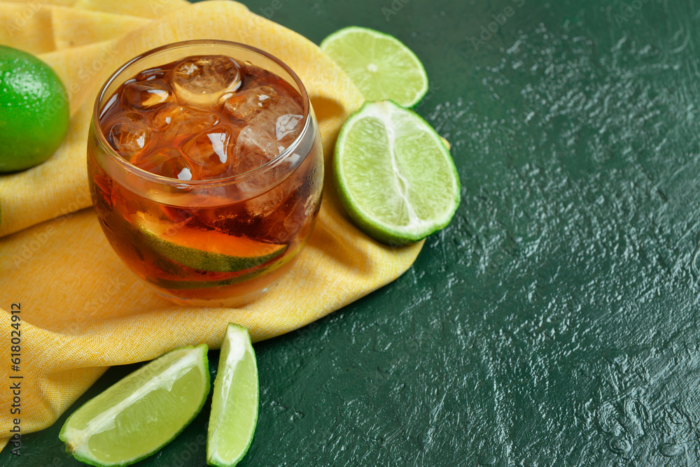 Glass of cold Cuba Libre cocktail on green background