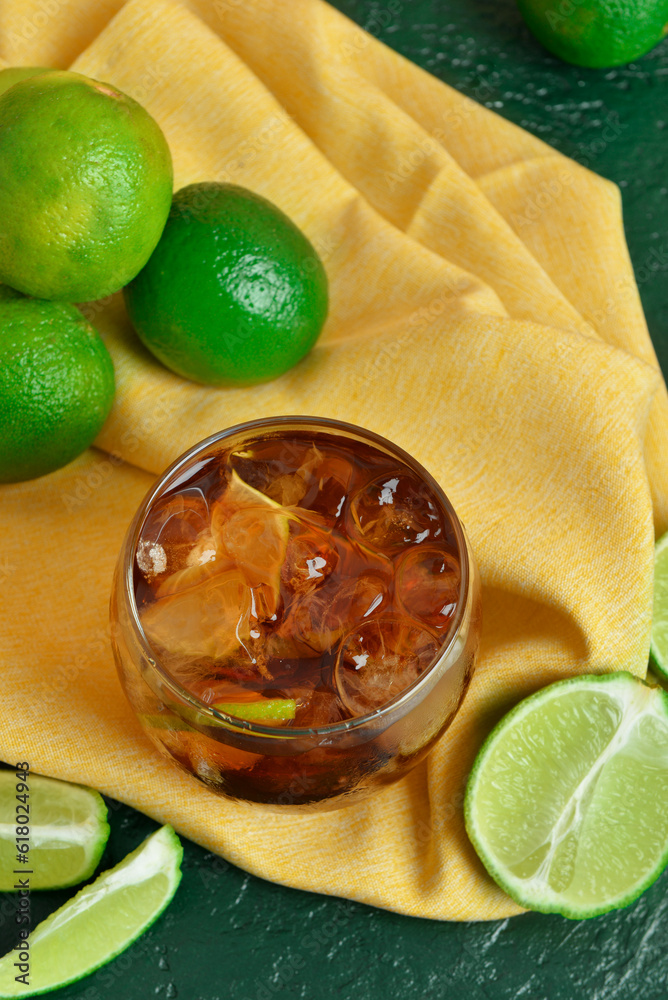 Glass of cold Cuba Libre cocktail on green background