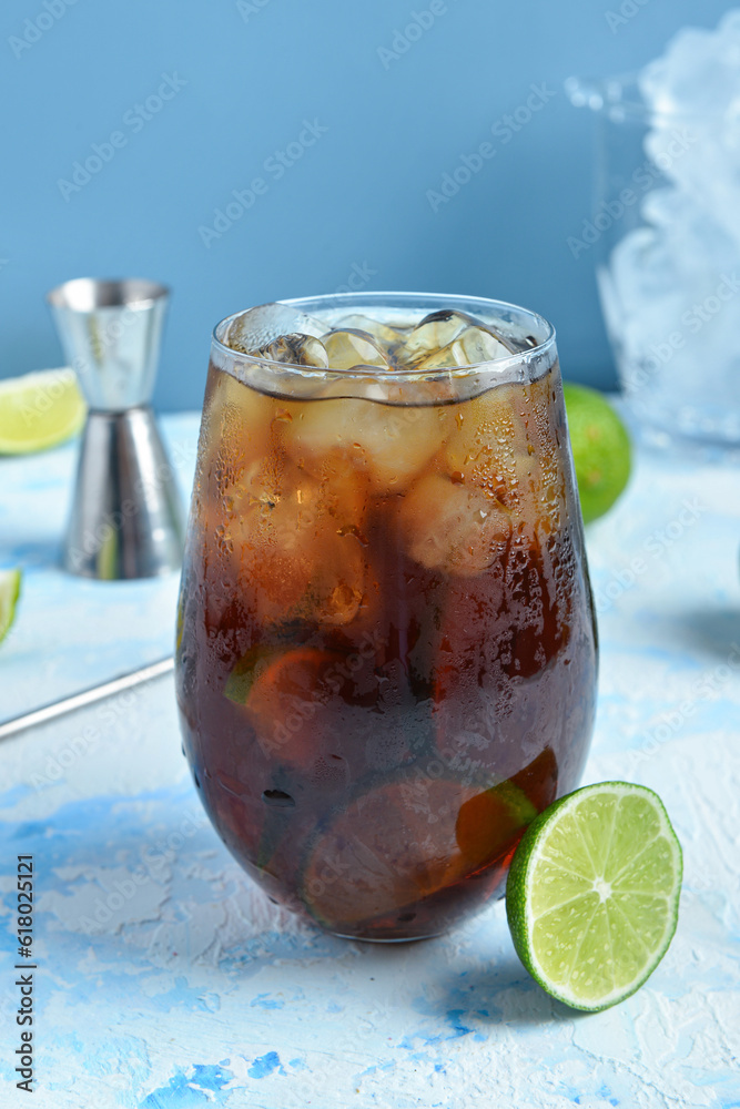 Glass of cold Cuba Libre cocktail on blue background