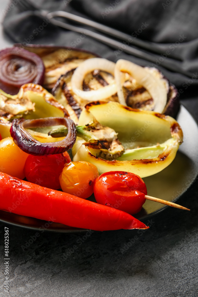 Plate with tasty grilled vegetables on black background