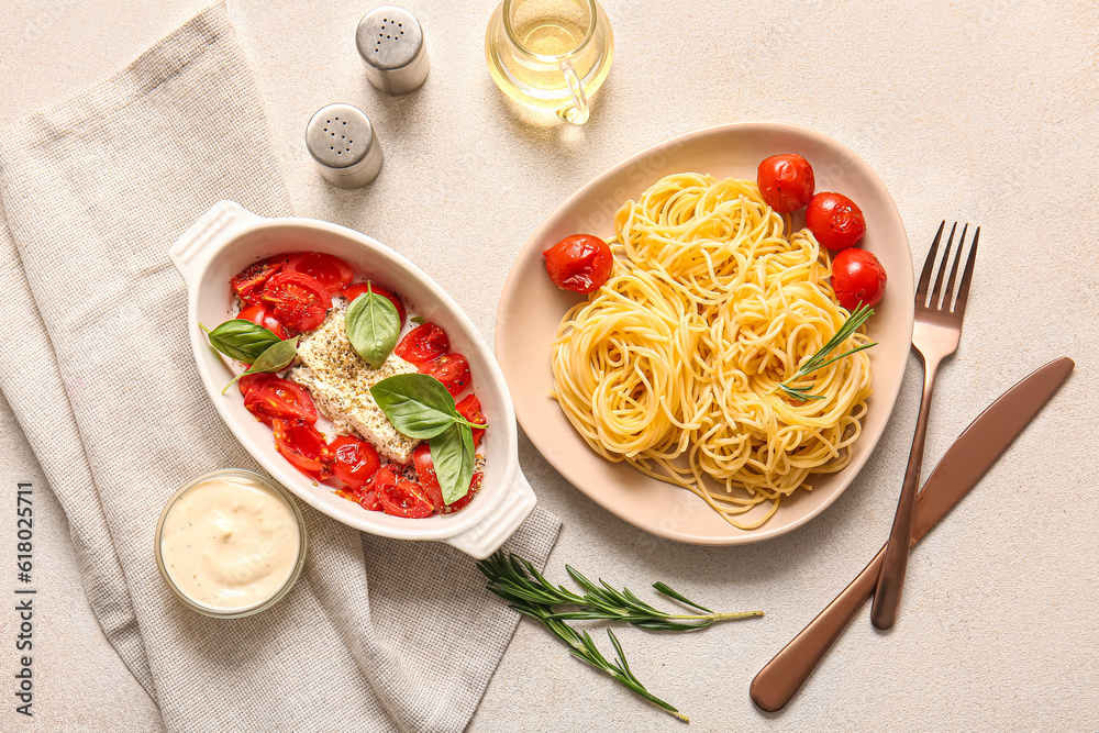 Baking dish with tasty tomatoes, feta cheese and pasta on light background