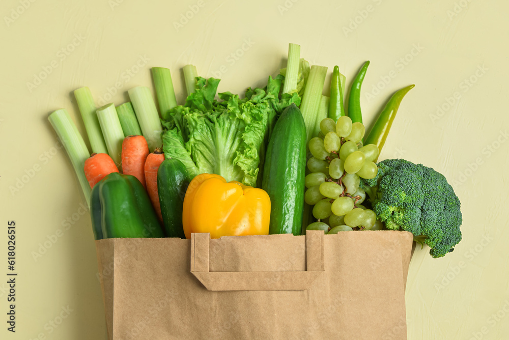 Paper bag with fresh vegetables and fruits on beige background