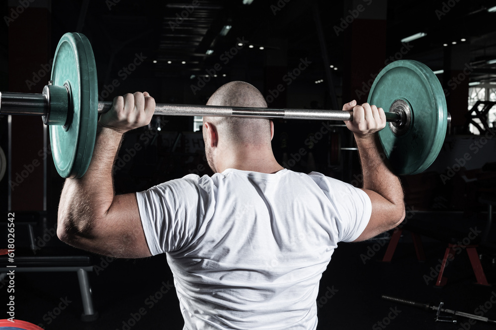 Male athlete lifts the barbell