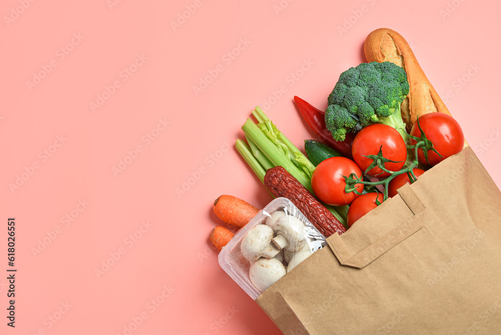 Paper bag with different products on pink background