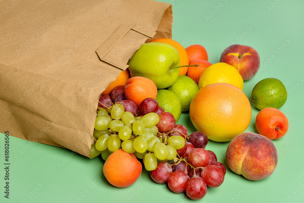 Paper bag with fresh fruits on turquoise background