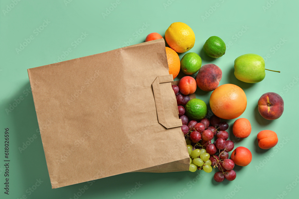 Paper bag with fresh fruits on turquoise background