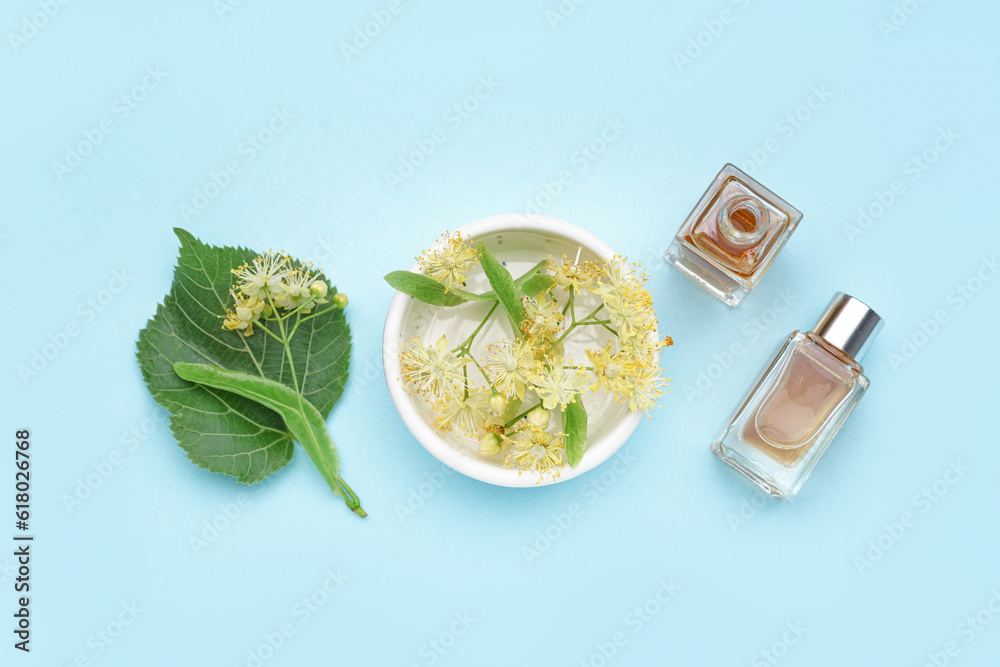 Composition with bottles of essential oil and fresh linden flowers on color background