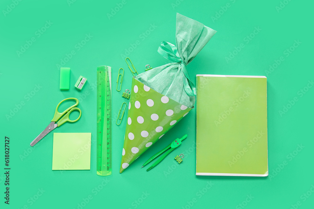 School cone with different stationery on green background