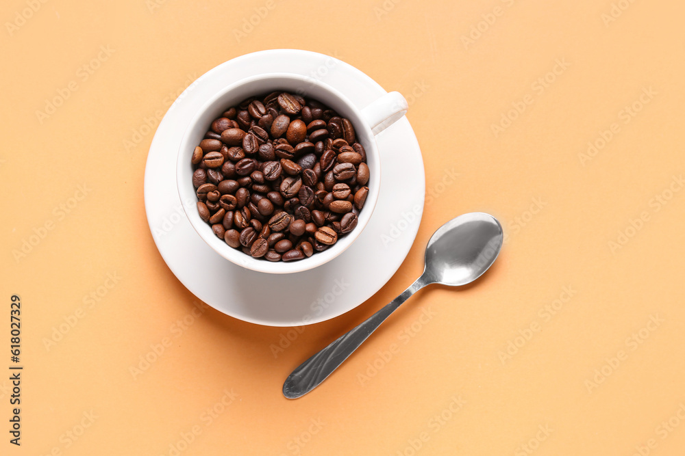 Cup of coffee beans on orange background