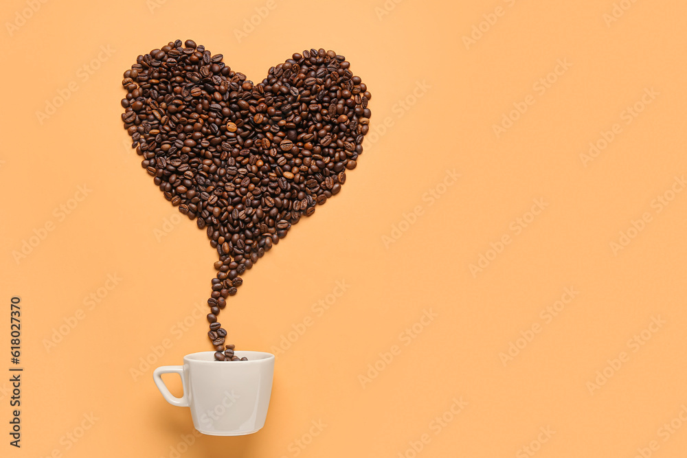 Coffee beans spilled from cup in shape of heart on orange background